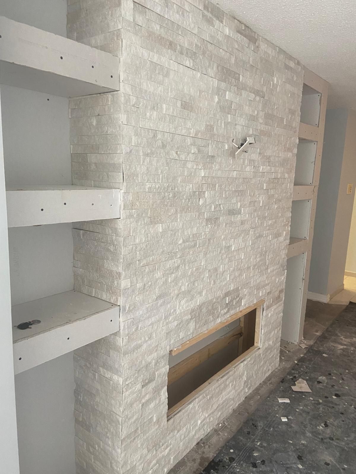 White stacked stone fireplace wall with open shelving on both sides
